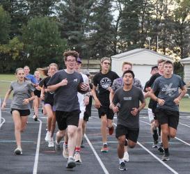 Cross Country Team Carries in Game Ball