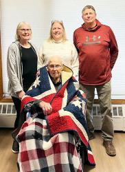 Pictured are Arliss Hein, wrapped in his Quilt of Valor, surrounded by his children, Colleen Bestge, Pam Berger, Randy Hein.