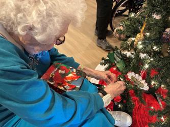 Elnora Dierks places an ornament on the Christmas Tree of Love that was created through the Maple Lawn Senior Care Christmas Adventure.